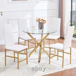 4 chaises de salle à manger blanches en faux cuir et table à manger ronde en verre transparent avec pieds dorés.