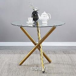 4 chaises de salle à manger blanches en faux cuir et table à manger ronde en verre transparent avec pieds dorés.